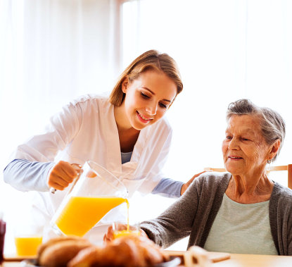 staff pouring juice to elder woman's glass
